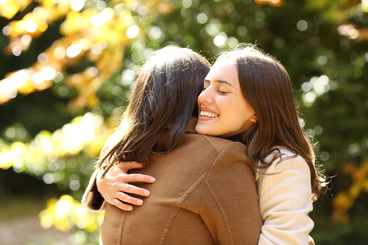Happy friends meeting and hugging in a park in autumn